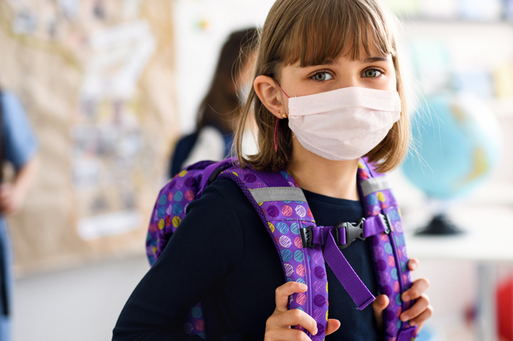 Young female student wearing a mask and backpack.